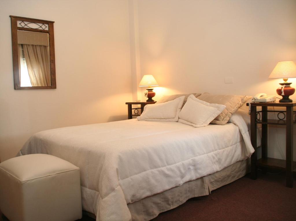 a bedroom with a large white bed with two lamps at Hotel Ariosto in Mendoza
