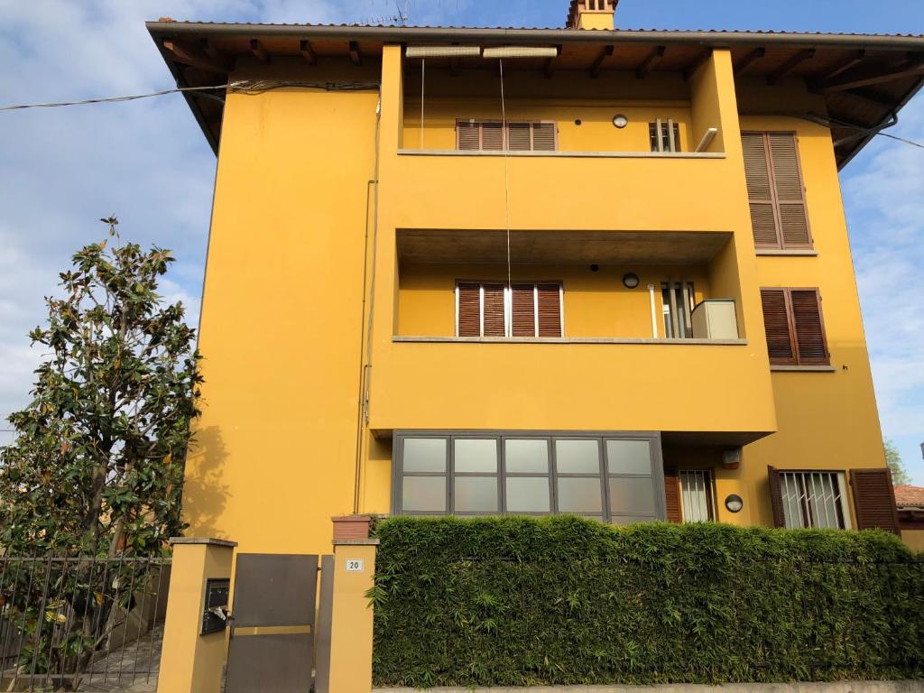 un edificio amarillo con ventanas y un seto en Michelino's house en Bolonia