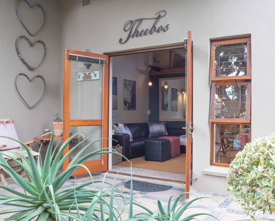 une porte ouverte sur un salon avec un canapé dans l'établissement Theebos, à Strand