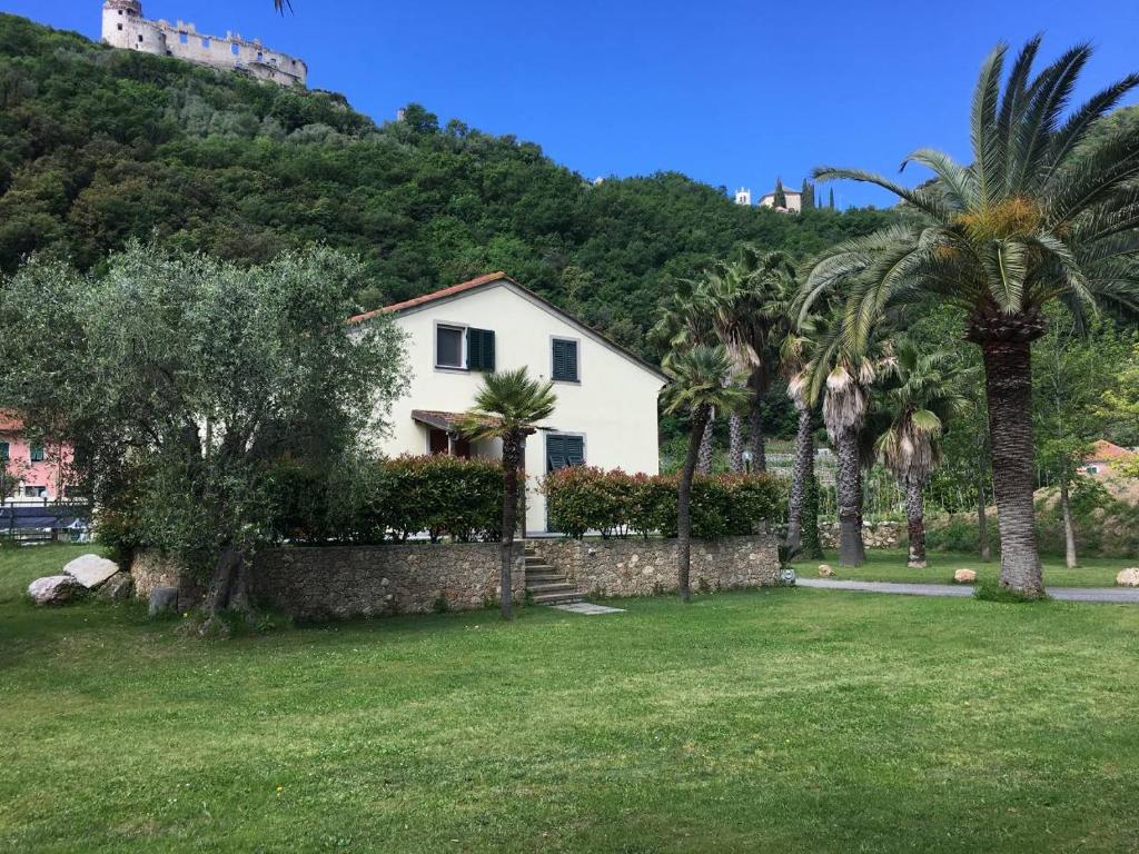 a white house with palm trees in a yard at Charming Ligurian Riviera House in Finale Ligure