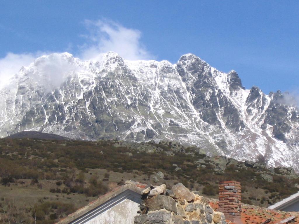 una montaña cubierta de nieve frente a una casa en Hostal Asador La Montaña, en Triollo