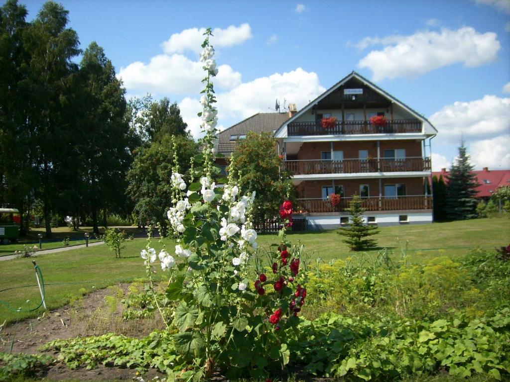 une grande maison avec un grand jardin fleuri en face dans l'établissement Haus Panorama, à Tylkowo