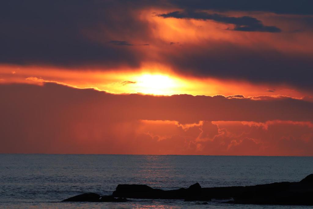 a sunset over the ocean with rocks in the foreground at West Coast Lodge in Lahinch