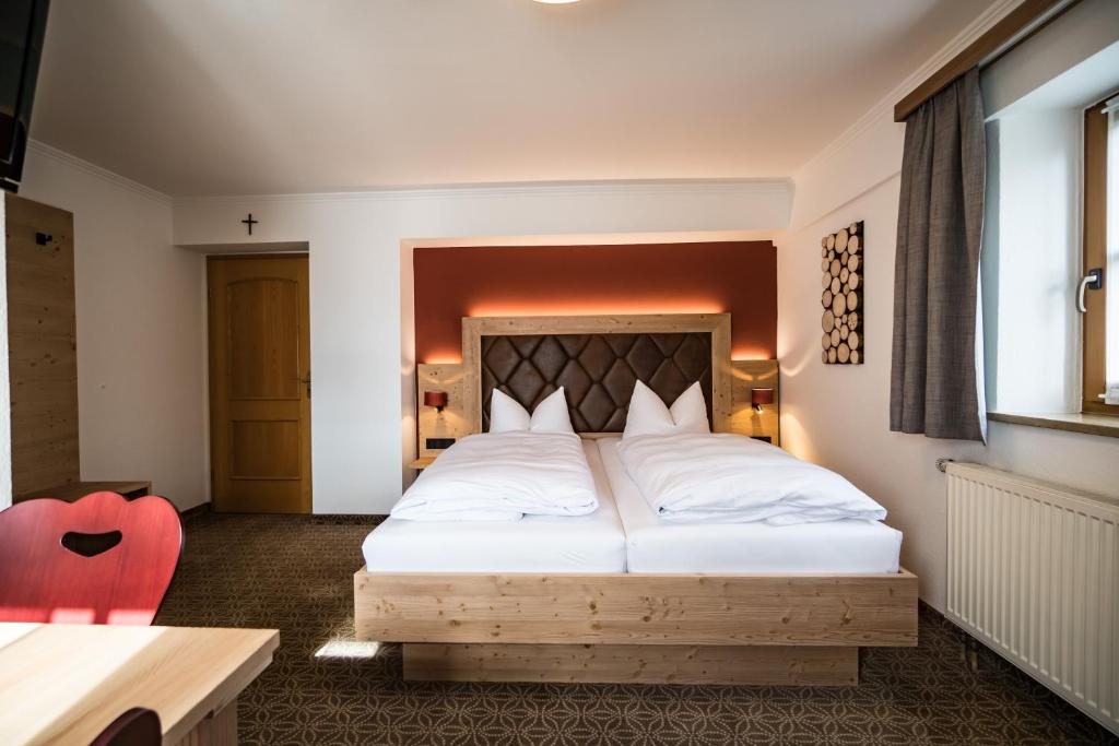 a bedroom with a large white bed with a red chair at Hohenester Gasthaus & Hotel in Markt Indersdorf