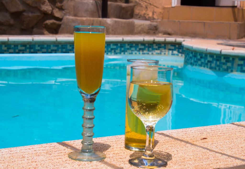 two glasses of wine sitting next to a swimming pool at YoIeli Guest House in Windhoek