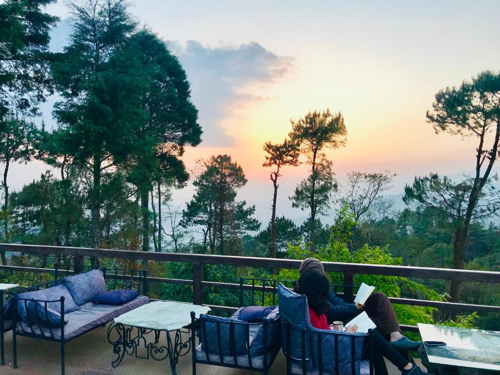 two people sitting on a balcony reading a book at Hotel At The End Of The Universe in Nagarkot