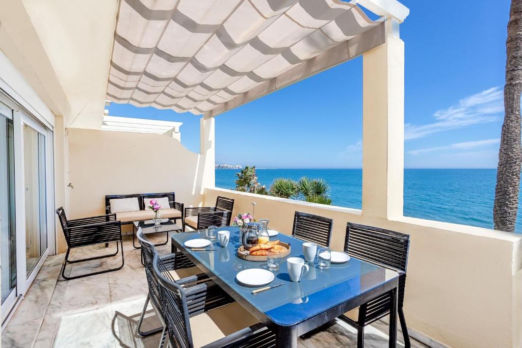 een eetkamer met een tafel en stoelen en de oceaan bij Beach View Playa Del Moral in Estepona