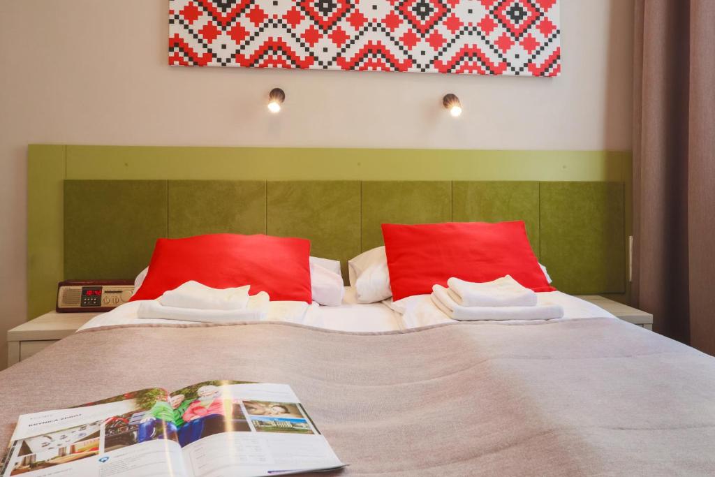 łóżko z czerwonymi poduszkami i książką w obiekcie Hotel *** NAT Krynica Zdrój w mieście Krynica Zdrój