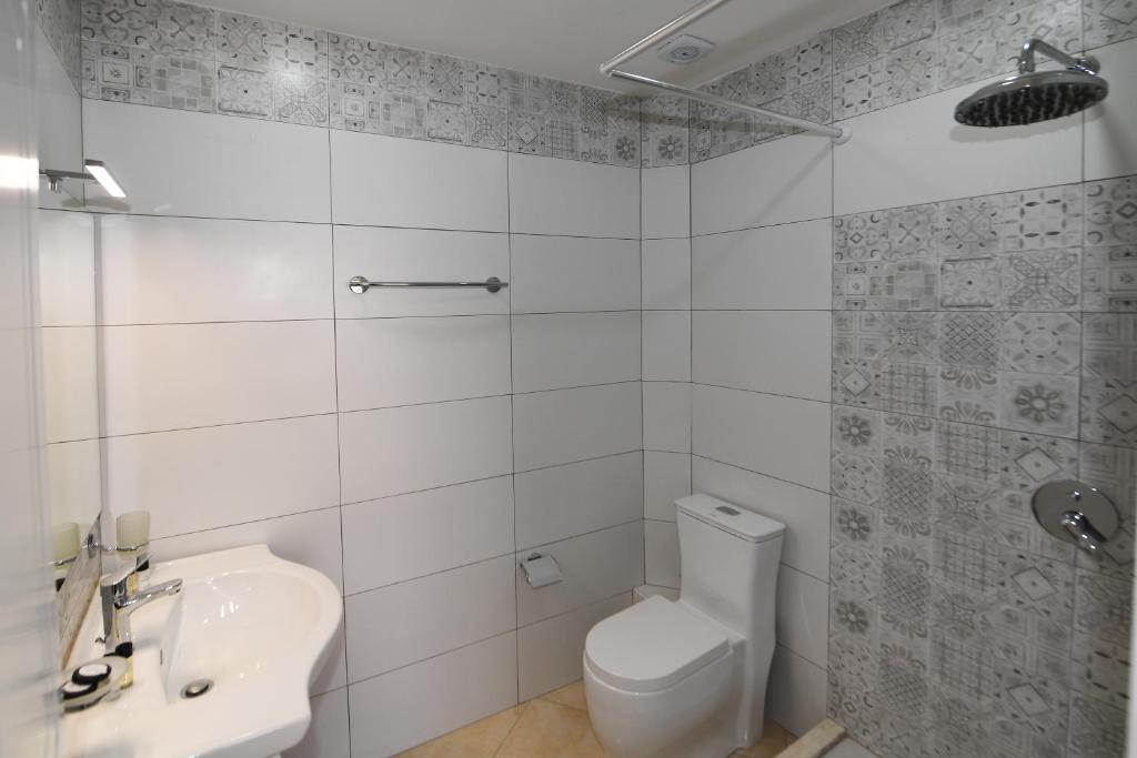 Un baño blanco con inodoro y lavabo. en Promenade Hotel, en Shkodër