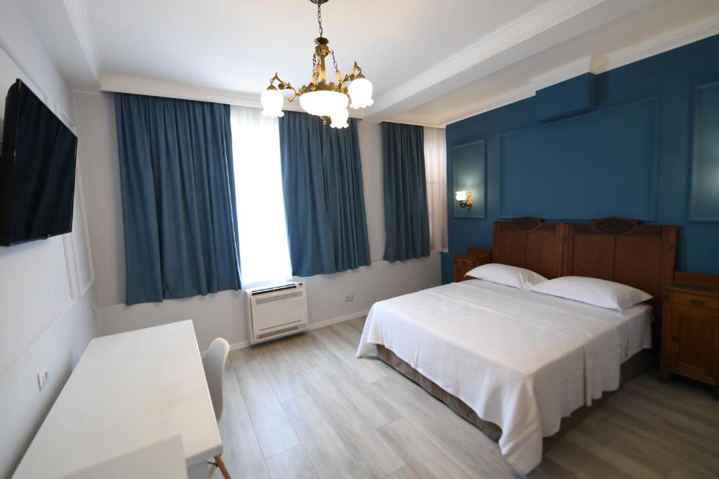 um quarto com uma cama, paredes azuis e um lustre em Promenade Hotel em Shkodër