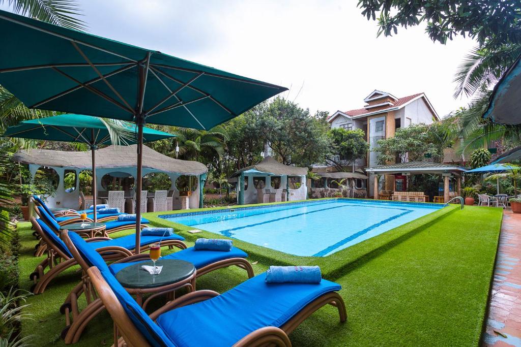 a pool with chairs and umbrellas next to a house at Comfort Gardens in Nairobi