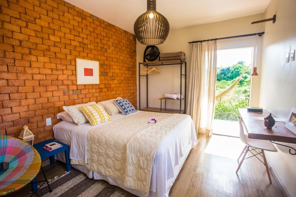 a bedroom with a bed and a brick wall at Vilarejo Guesthouse - Silêncio e Aconchego in Alto Paraíso de Goiás