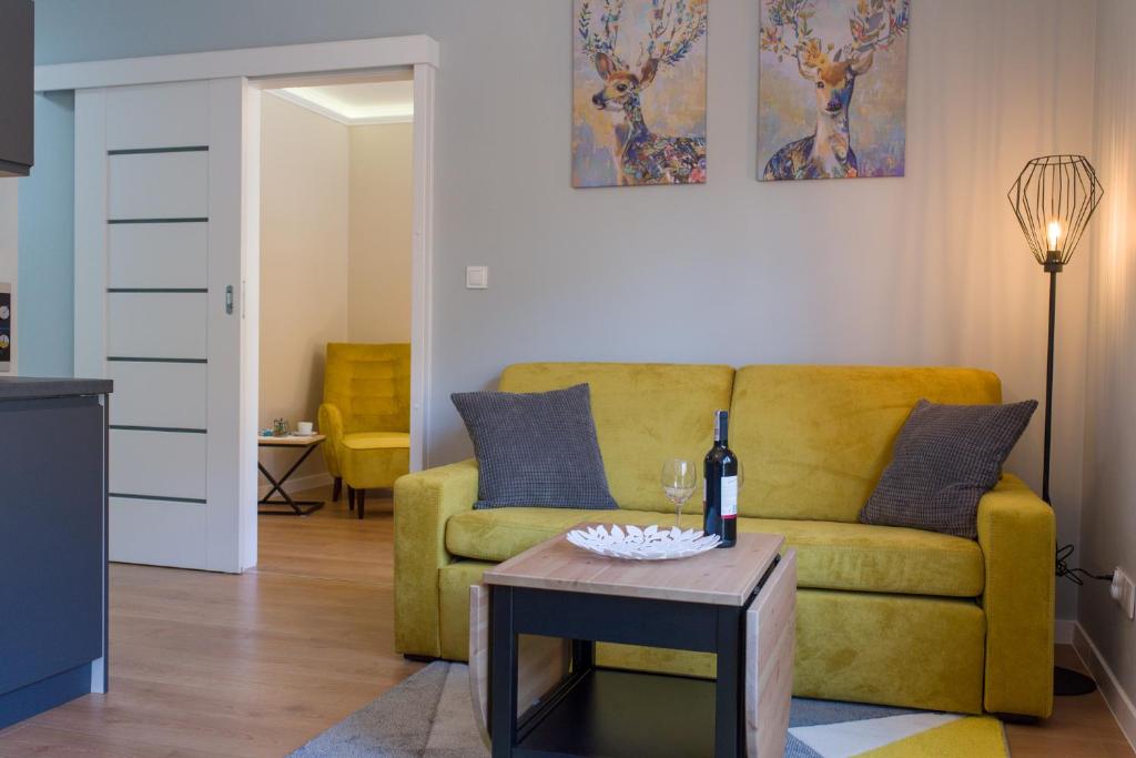 ein Wohnzimmer mit einem gelben Sofa und einem Tisch in der Unterkunft Go2Krynica - Cicha in Krynica-Zdrój