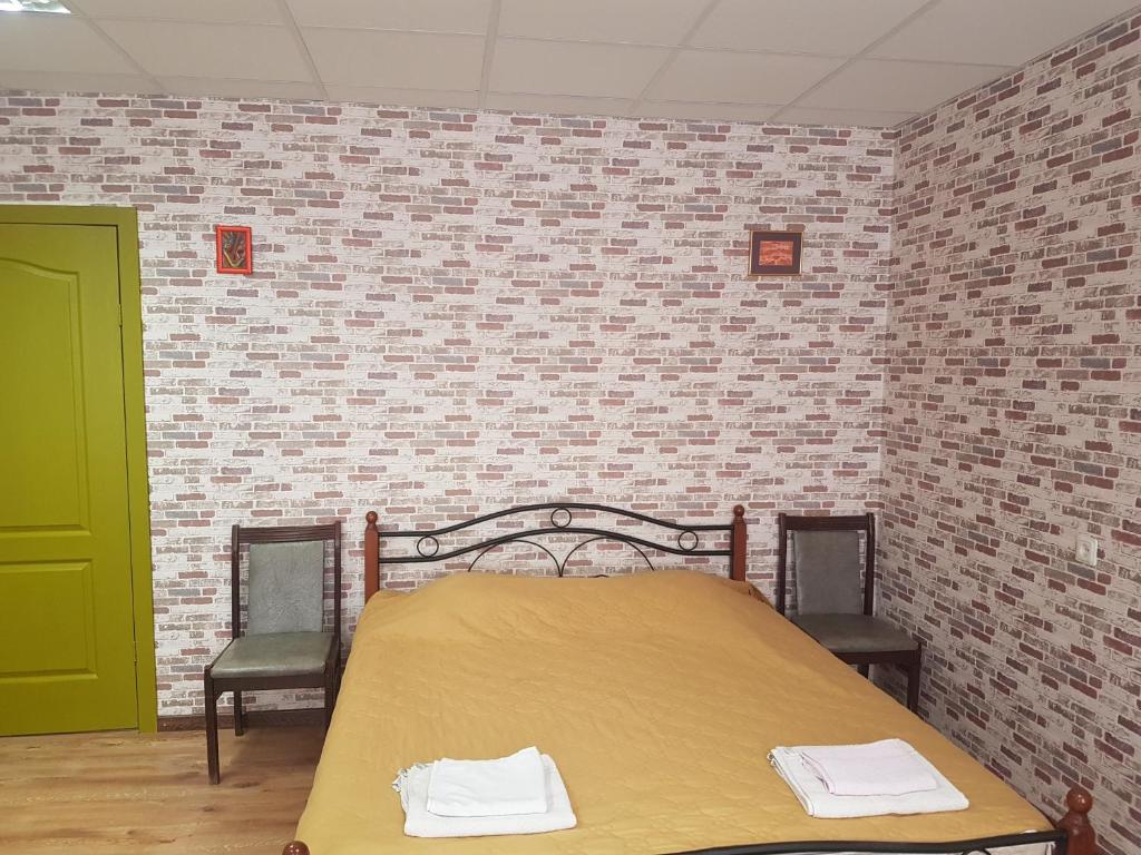 ein Schlafzimmer mit einem Bett mit 2 Stühlen und einer Ziegelwand in der Unterkunft Apartament Erfolg 11 in Daugavpils