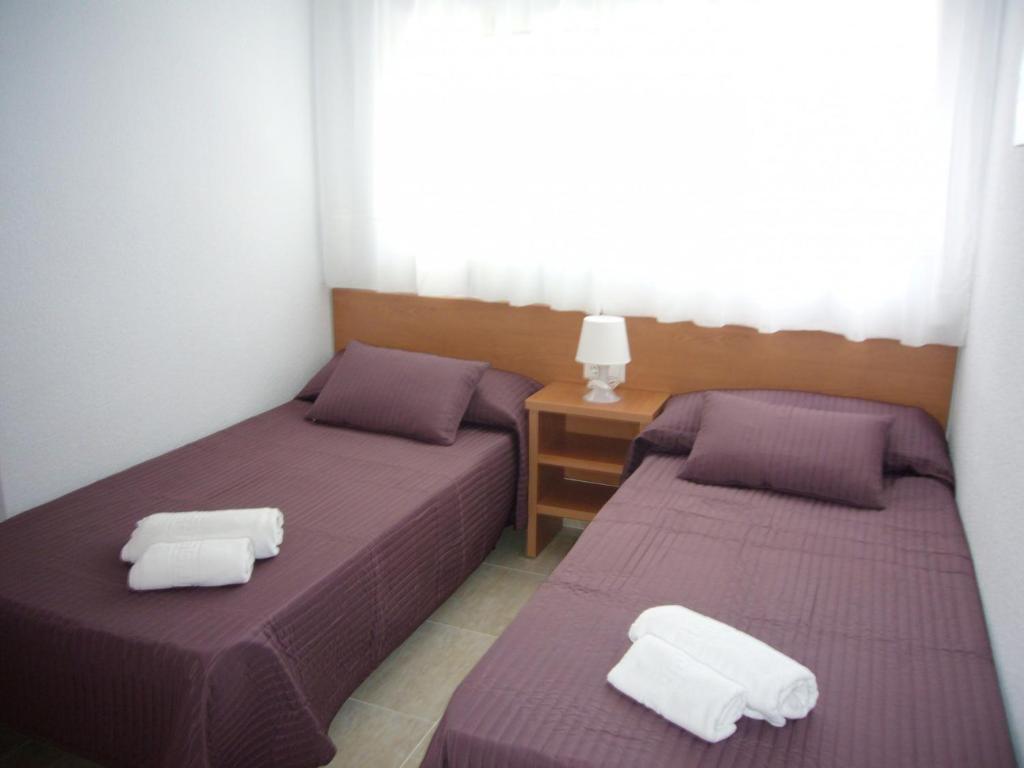 two beds in a room with purple sheets and white pillows at Acacias 4 - Fincas Arena in Benidorm