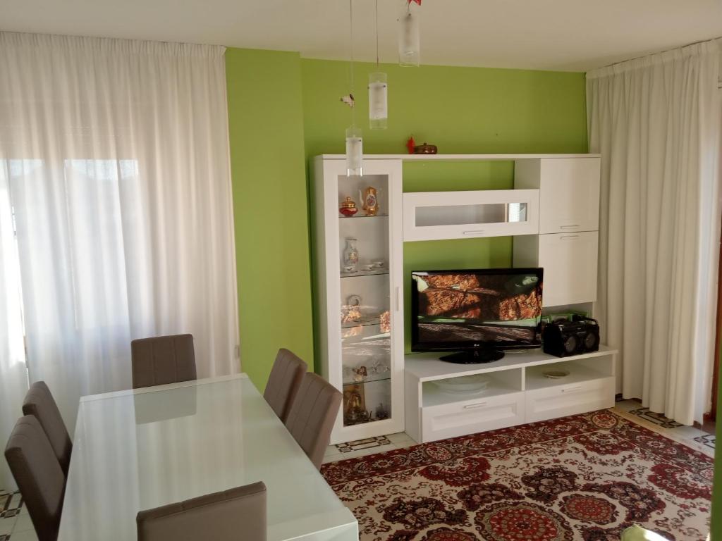 a dining room with a white table and a television at Via Genova Apartment in Olbia