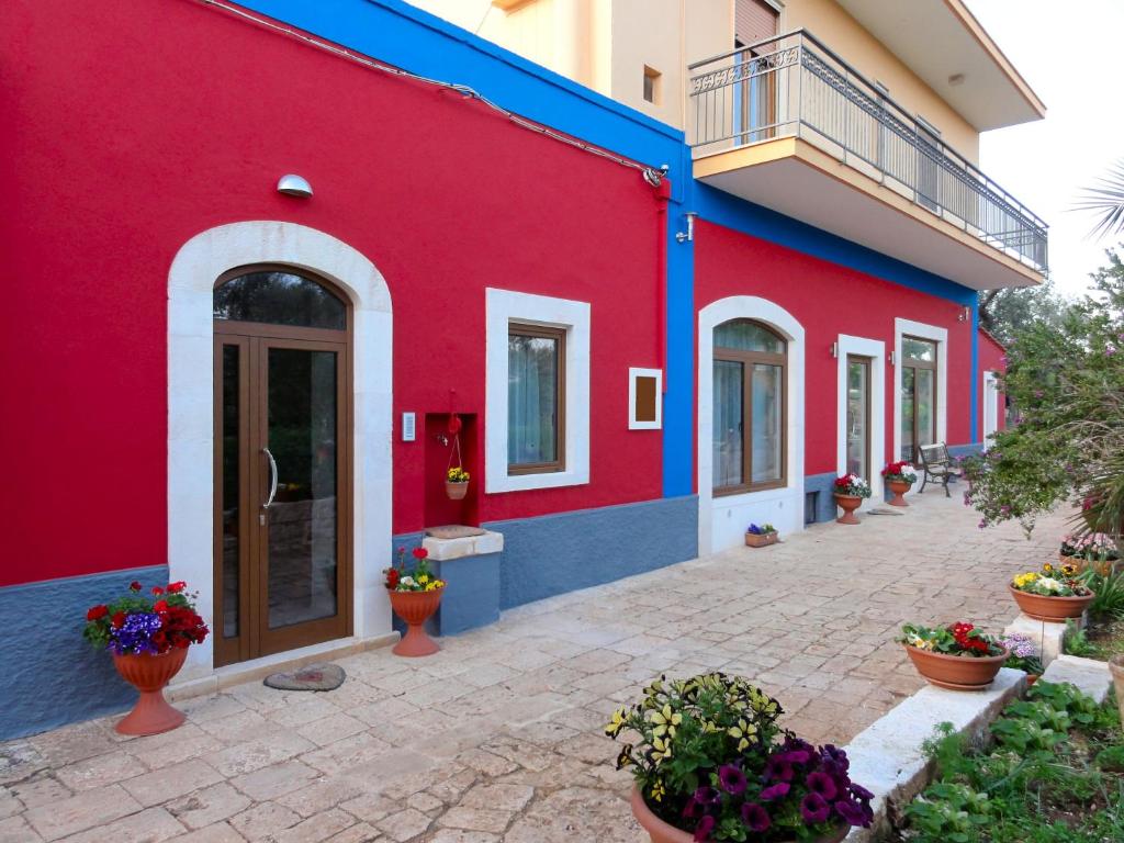 un edificio rojo y azul con flores en su interior en Ape Rossa, en Castellana Grotte