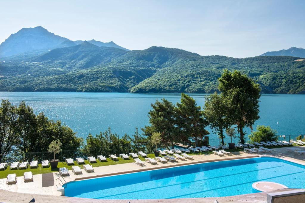une piscine avec des chaises et une vue sur un lac dans l'établissement L'Ecrin du Lac, à Chorges