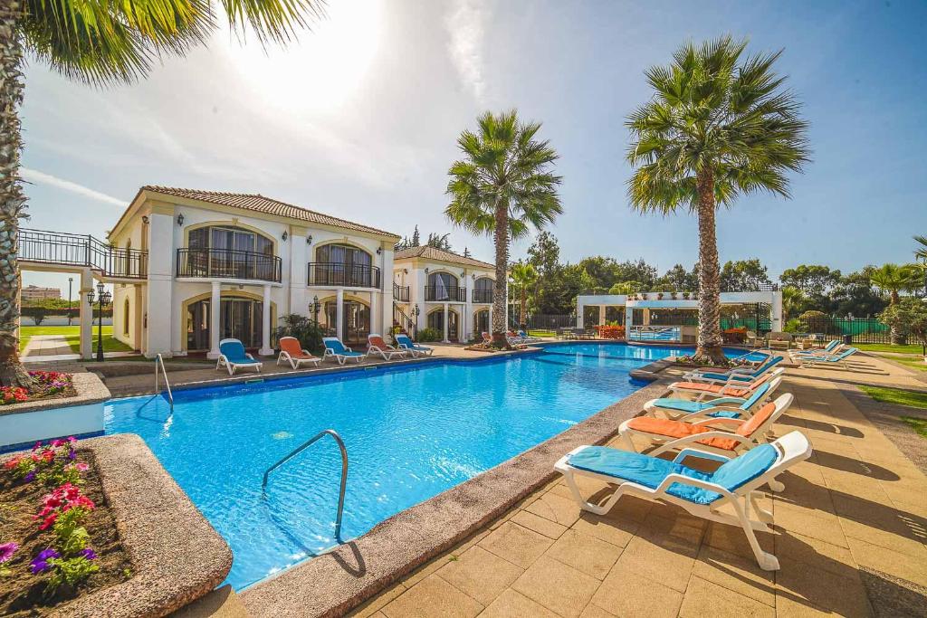 a swimming pool with lounge chairs and palm trees at Aparthotel Serena Dream in La Serena