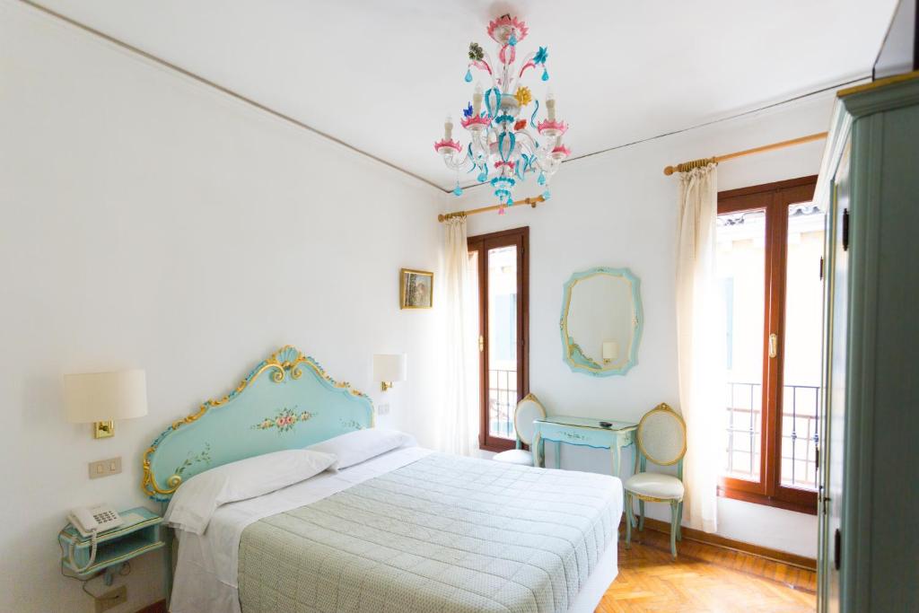 Habitación blanca con cama y espejo en Hotel Serenissima, en Venecia