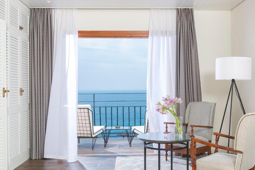 
a living room with a table, chairs and a window at Hotel Santa Marta in Lloret de Mar

