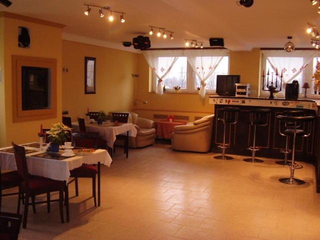 ein Wohnzimmer mit Tischen und Stühlen sowie eine Küche in der Unterkunft Zajazd Batory in Chorzów