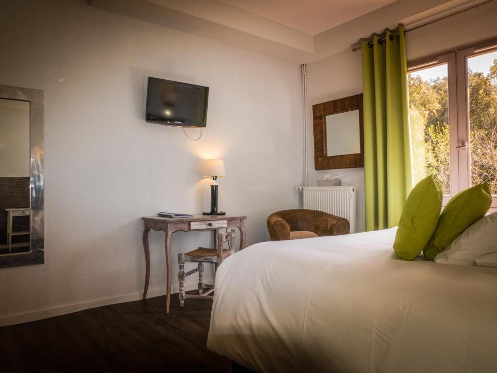 a bedroom with a bed and a table and a window at Le Belvedere in Vallon-Pont-dʼArc