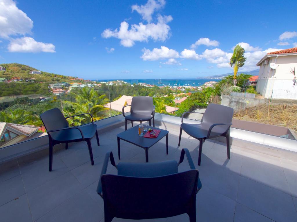 een balkon met stoelen en een tafel en uitzicht op de oceaan bij LES VILLAS GLACY in Les Trois-Îlets