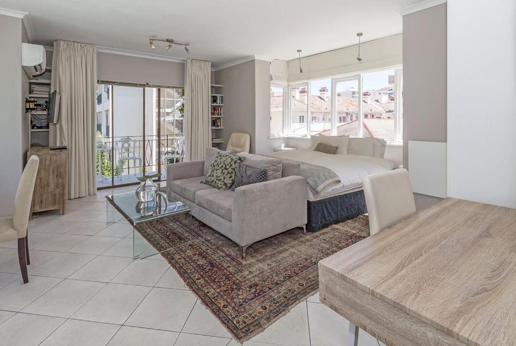a living room with a bed and a couch at Cosy and Classy Sea Point Apartment in Cape Town
