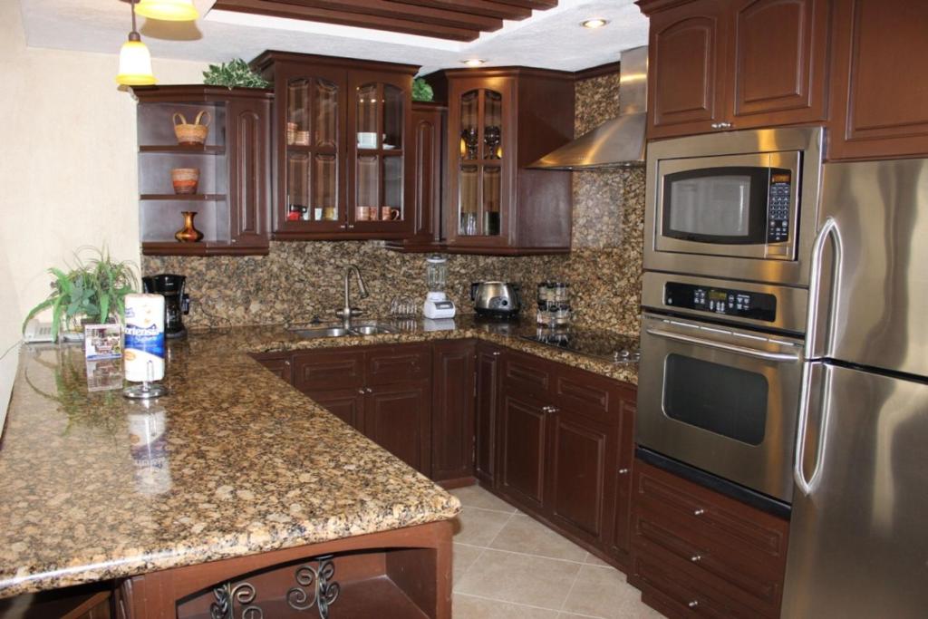 una cocina con armarios de madera y electrodomésticos de acero inoxidable en Sonoran Sky 1BR Upper SKY 1406 by Casago, en Puerto Peñasco