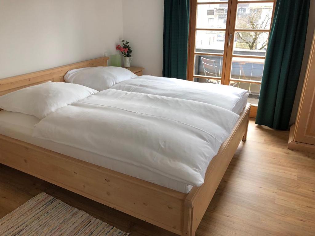 una camera da letto con un grande letto con lenzuola bianche di Landgasthaus zum Altwirt Reichersbeuern a Reichersbeuern