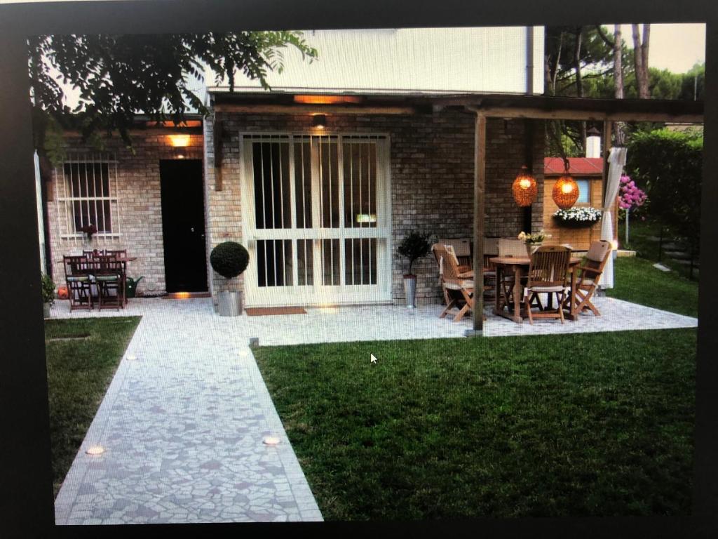 a patio with a table and chairs in front of a house at Jesolo pineta oasi verde ,spiaggia e mare in Lido di Jesolo
