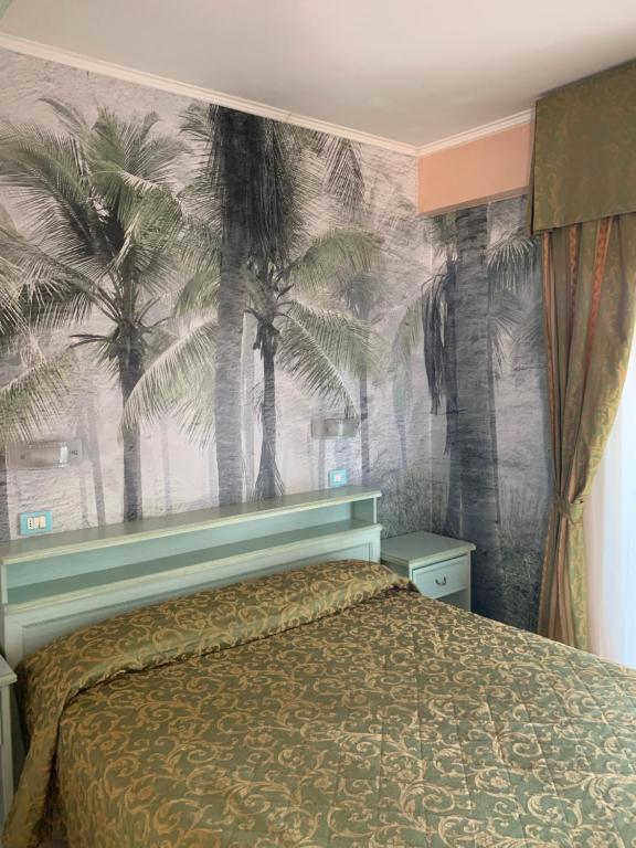 リッチョーネにあるHotel Residence Velieroのベッドルーム1室(ヤシの木の壁にベッド1台付)