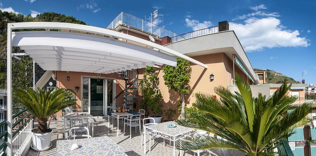 patio con tavoli e sedie sotto un ombrellone bianco di B&B Amalfè a Maiori