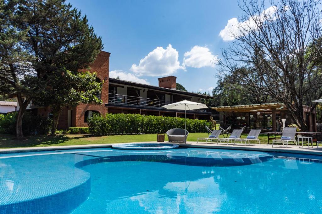 a swimming pool with chairs and a house at Hotel Boutique Unico Avandaro in Valle de Bravo