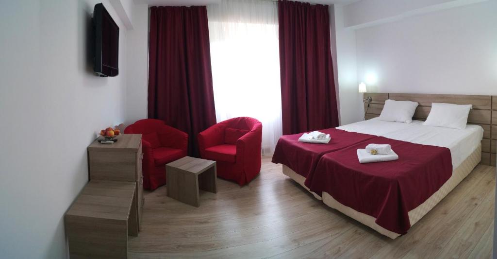Hotel Otopeni في أوتوبيني: غرفة بالفندق سرير وكرسي احمر