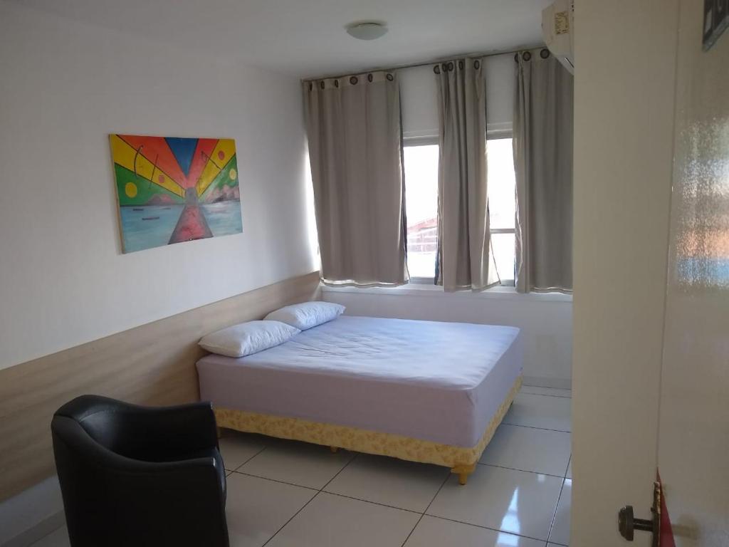 a small bedroom with a bed and a chair at Piaui Apart Hotel in Teresina