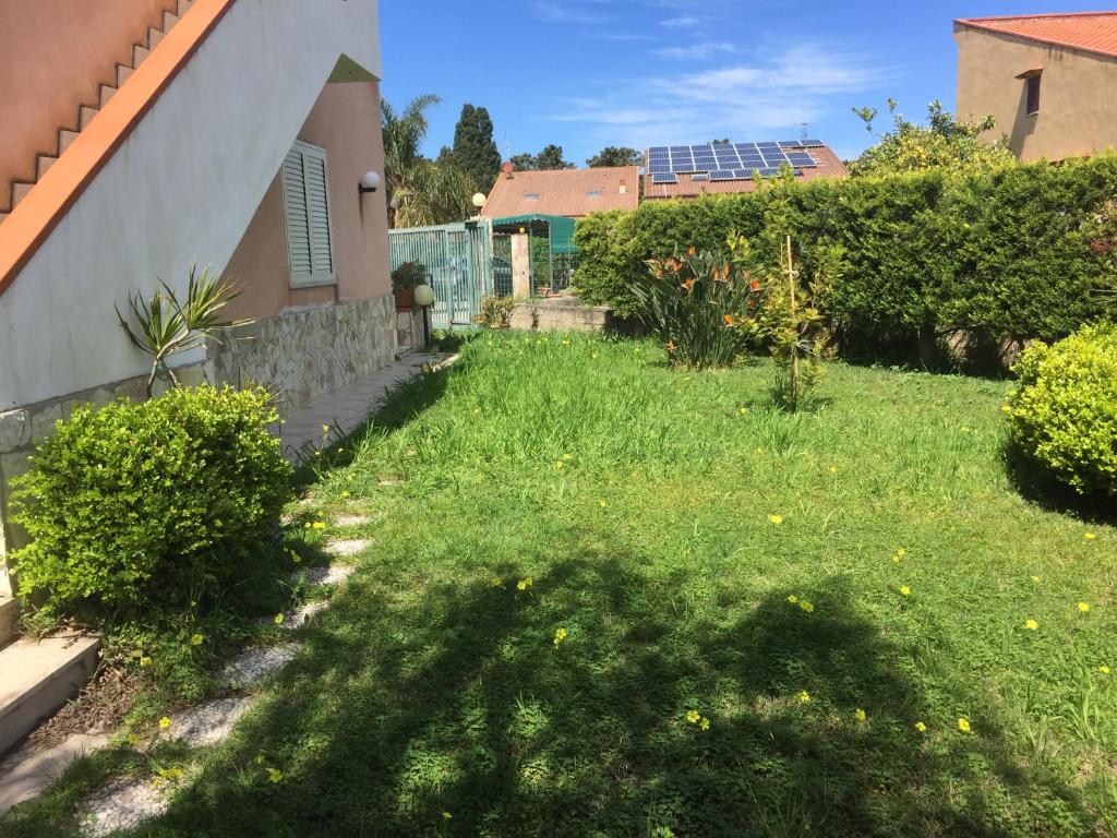 a yard with green grass and a house at Villetta immersa nel verde ma vicina al mare in Lascari