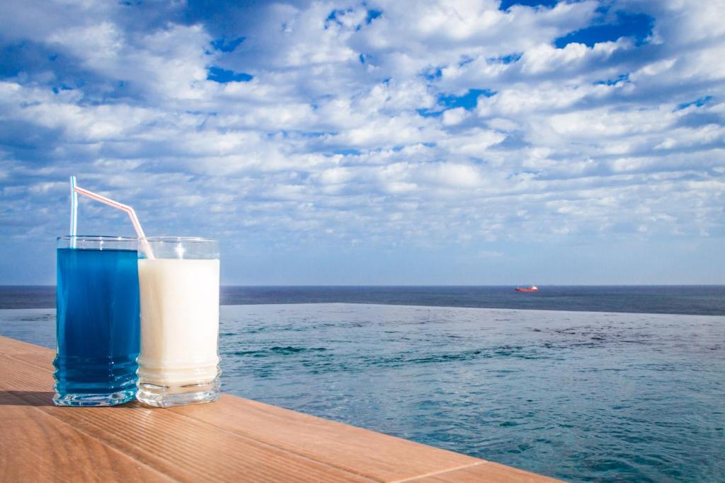 a glass of milk sitting on a table next to the ocean at Lux Apartments in Xgħajra
