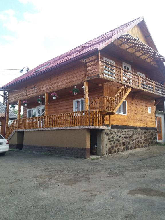Pensiunea Poienita في Budeşti: منزل خشبي مع شرفة وسطح