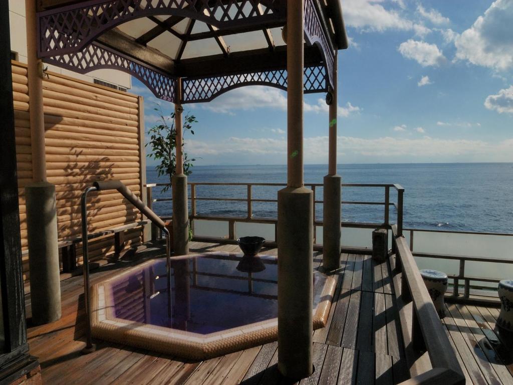 a hot tub on a deck with the ocean in the background at Inatori Tokai Hotel Yuen in Higashiizu