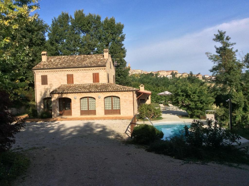 une grande maison en briques avec une piscine en face de celle-ci dans l'établissement Villa Santa Maria, à Montegiorgio
