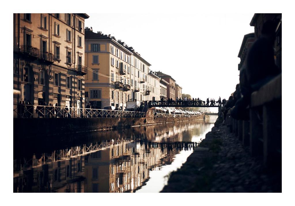 een reflectie van gebouwen in het water van een kanaal bij Taking a WALK in the beating HEART of NAVIGLI in Milaan