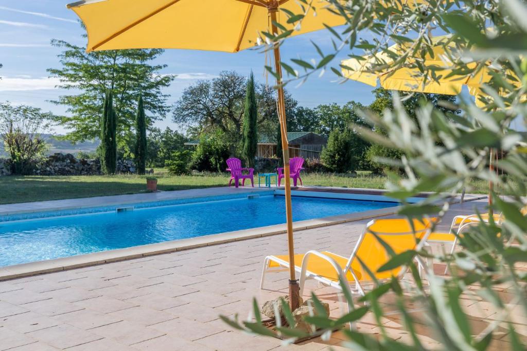 a pool with chairs and umbrellas next to a swimming pool at Domaine de Sonnard in Castéra-Verduzan