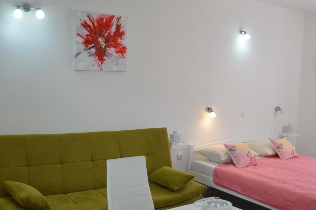 a bedroom with a bed and a couch and a painting at Downtown Sweet Studio in Novalja