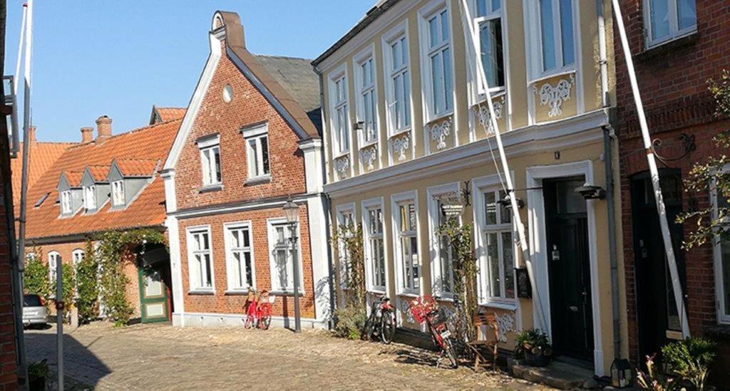um grupo de edifícios antigos numa rua em To sammenhængende værelser med udgang til have em Ribe