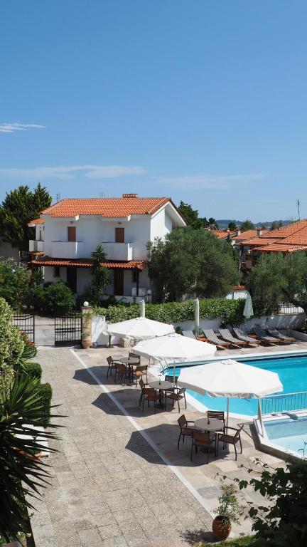 a group of tables and umbrellas next to a swimming pool at Evridiki Hotel in Fourka