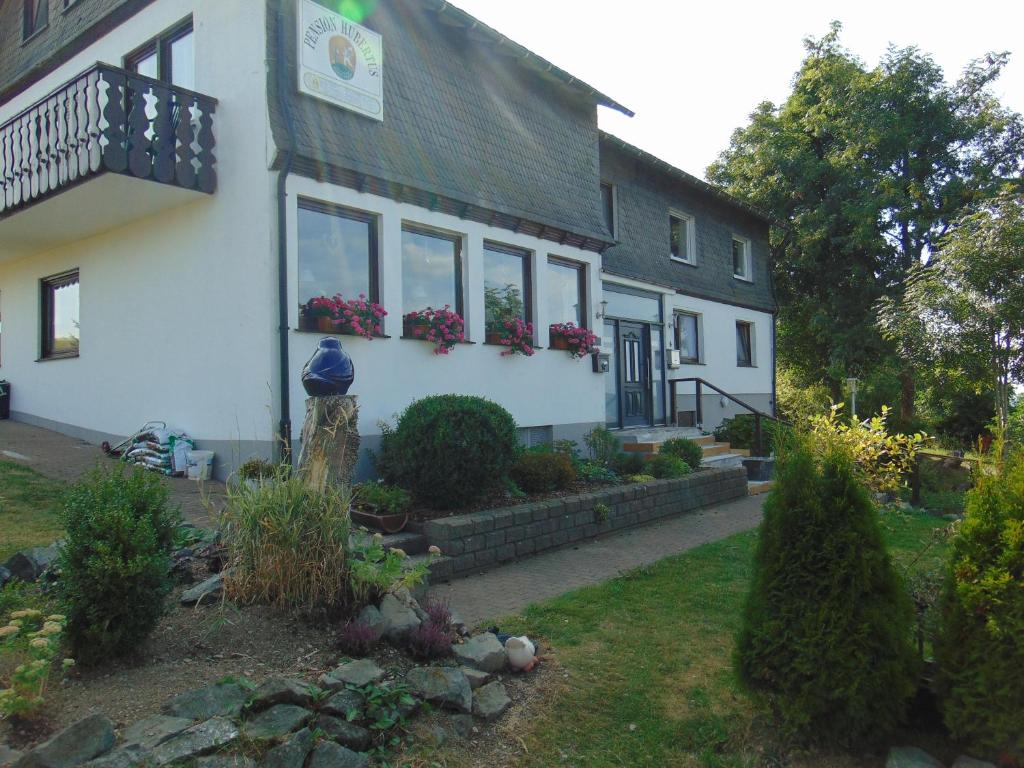 una casa blanca con flores en las ventanas en Pension Hubertus en Winterberg