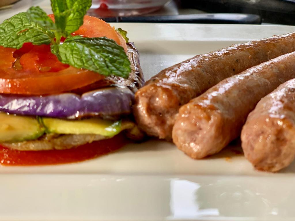 a plate with a sausage and a hamburger and tomatoes at Villino Eleonora in Parghelia