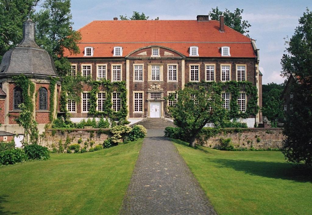 ein großes Backsteingebäude mit rotem Dach in der Unterkunft Hotel Schloss Wilkinghege in Münster